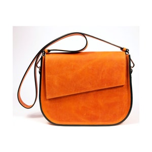 K&ouml;nnte beinhalten: Eine braune Lederschultertasche mit schwarzem Besatz. Die Tasche hat einen Klappenverschluss und einen langen verstellbaren Riemen.