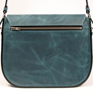 May include: A teal blue leather satchel bag with a zipper closure and a black strap.