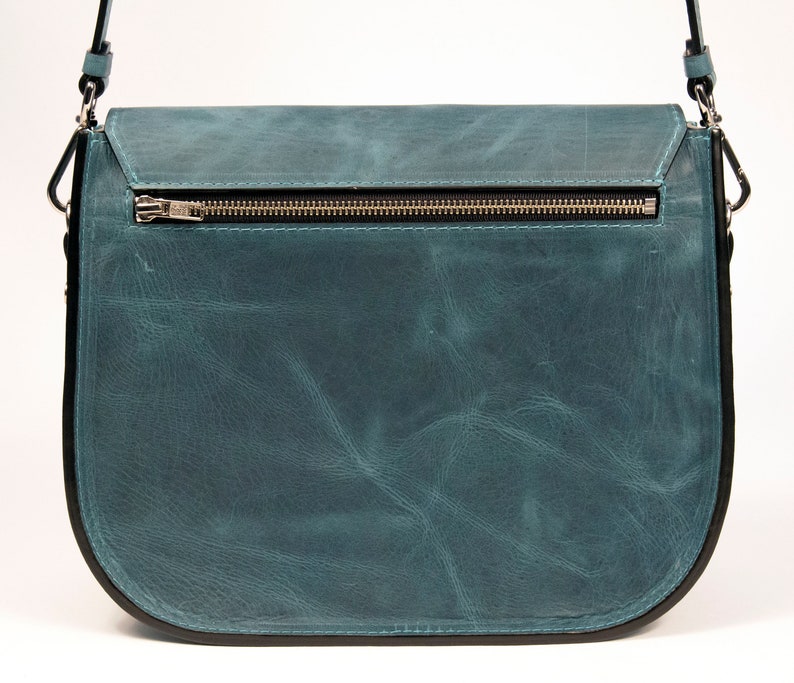May include: A teal blue leather satchel bag with a zipper closure and a black strap.