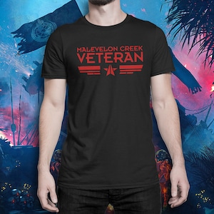 May include: A black t-shirt with red text that reads "Malevelon Creek Veteran" with a red star and wings.