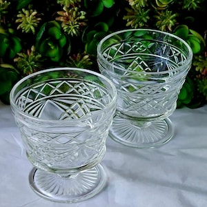 May include: Two clear glass dessert dishes with a cut glass design. The dishes have a pedestal base.