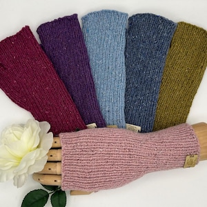 May include: Seven pairs of fingerless gloves in various colors, including burgundy, purple, light blue, dark blue, green, and pink. The gloves are made of a soft, textured yarn.