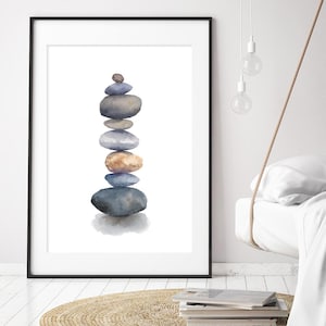 May include: A framed print showing a watercolour painting of balanced stones in blue, grey, and brown hues. The artwork is set against a white backdrop, within a black frame. The print is a minimalist piece of art, suitable for a bedroom.