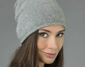 May include: A gray knitted beanie hat with a slouchy fit. The hat is made of soft, comfortable material and is perfect for keeping your head warm in the winter.