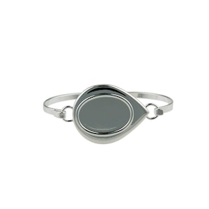 May include: A silver-toned metal bangle bracelet featuring a central teardrop-shaped bezel setting. The smooth, reflective surface of the teardrop frame is connected to the thin, circular band by two small jump rings on either side of the setting.