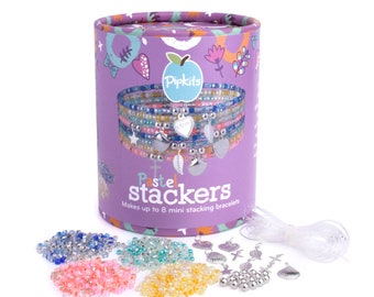 May include: A craft kit for making bracelets. The kit includes a variety of colorful beads, silver charms, and clear elastic string. The box is purple and features the text "Pastel Stackers" and "Makes up to 8 mini stacking bracelets".