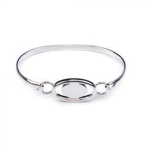 May include: A silver bangle bracelet with a circular cutout in the center. The bracelet is open and has a simple design.