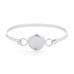 Könnte beinhalten: Ein silbernes Armkettchen mit einem runden, glatten, leeren Scheibenanhänger. Das Armband hat ein schlichtes, elegantes Design.