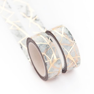 K&ouml;nnte beinhalten: Zwei Rollen Washi-Tape mit Marmor- und Gold-Design. Das Band ist wei&szlig; mit goldenen Adern und schwarzem Hintergrund.