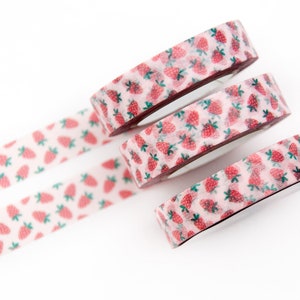 May include: Four rolls of pink and white washi tape with a strawberry pattern. The tape is rolled up and stacked on top of each other.