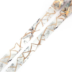 K&ouml;nnte beinhalten: Zwei Rollen wei&szlig;es und goldenes Washi-Tape mit Marmor- und Blattgoldmuster. Das Band befindet sich auf wei&szlig;em Hintergrund.