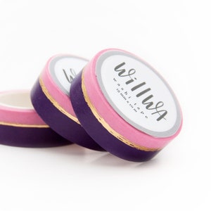 Puede incluir: Tres rollos de cinta washi en fila. La cinta es morada, rosa y dorada. La etiqueta de la cinta dice "willwa washi tape 15 mm x 10 m".