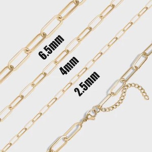 May include: Gold-coloured chain necklaces in various sizes: 6.5mm, 4mm, and 2.5mm. The chains are displayed diagonally, showcasing their elongated link design. One chain features a clasp and an extender chain.