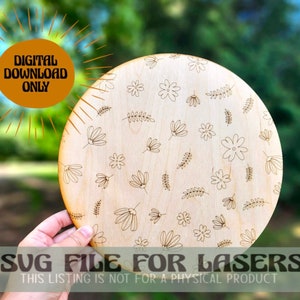 May include: A digital download SVG file for laser cutting a round wooden plaque with a floral pattern. The text "SVG FILE FOR LASERS" and "THIS LISTING IS NOT FOR A PHYSICAL PRODUCT" is printed on the image.