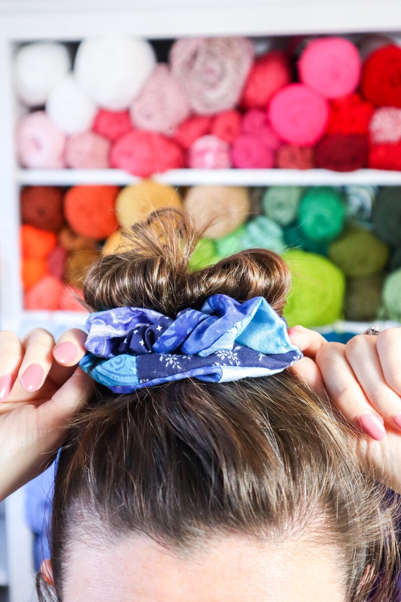 K&ouml;nnte beinhalten: Ein blaues und wei&szlig;es Stoffscrunchie, das das braune Haar einer Frau in einem Dutt h&auml;lt.