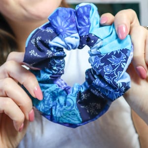 May include: A blue and white patterned scrunchie made from fabric scraps. The scrunchie is gathered and tied into a circle.