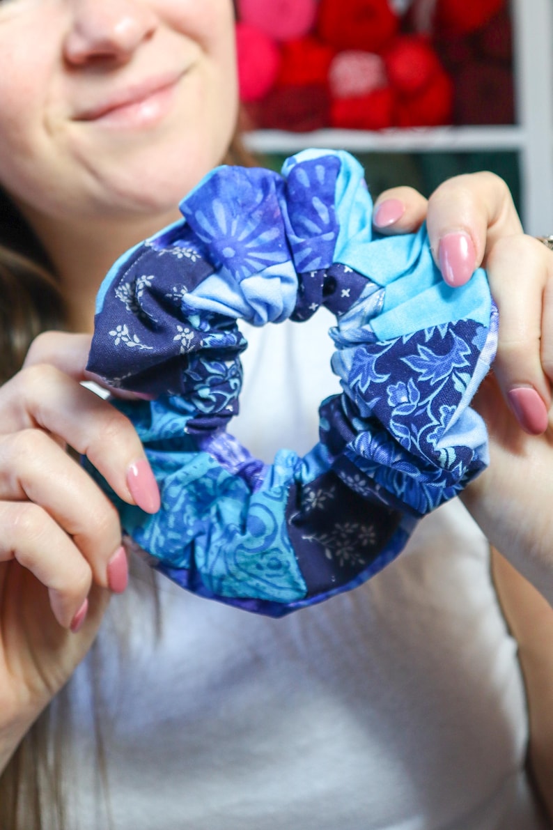 K&ouml;nnte beinhalten: Ein blauer und wei&szlig;er gemusterter Haargummi aus Stoffresten. Der Haargummi ist zusammengezogen und zu einem Kreis gebunden.