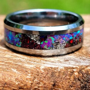 Könnte beinhalten: Ein silberner Wolframcarbid-Ring mit einem bunten Inlay aus irisierendem Opal, Rot und silbernem Glitzer.