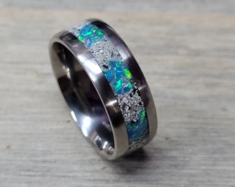 May include: A silver titanium ring with a band of iridescent opal and white specks.