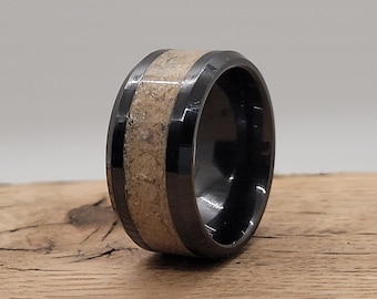 May include: A black and beige ring with a wood inlay. The ring is made of metal and has a polished finish.