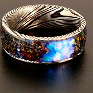 May include: A silver ring with a patterned band and a blue, green, and red opal inlay.