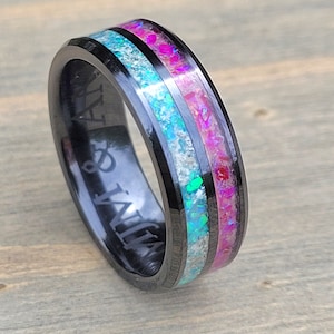 May include: Black tungsten carbide ring with a pink and blue opal inlay. The ring is engraved with the words "My & Jay".