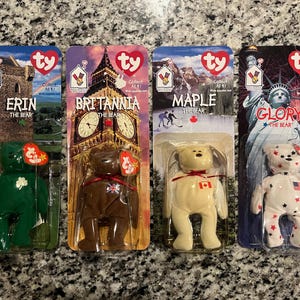 May include: Four Ty Beanie Baby plush toys in their original packaging. The toys are Erin the Bear, Britannia the Bear, Maple the Bear, and Glory the Bear. Each toy is wearing a different outfit representing a different country. Erin is wearing a green outfit with a shamrock, Britannia is wearing a brown outfit with a Union Jack, Maple is wearing a cream outfit with a Canadian flag, and Glory is wearing a white outfit with a US flag.