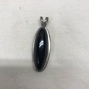 May include: A silver pendant with a black oval gemstone.