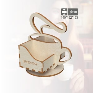 以下が含まれることがあります： 「GREEN TEA」の文字が入った、木製のティーカップ型オーガナイザー。サイズは140mm x 152mm x 153mm。明るい色の木材で作られており、カップの上には装飾的な渦巻きがあります。