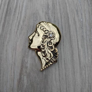 Gold Tone Metal and Clear Rhinestone 1920s Style Figure with Curly Hair and Feather Head Scarf