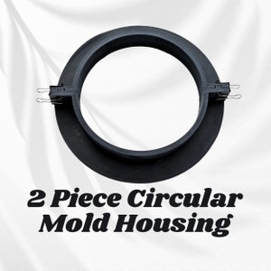 May include: A two-piece circular mold housing in black. The mold is round with a flat base and a raised circular wall. The two halves are connected with metal clips. Text on the image reads "2 Piece Circular Mold Housing."