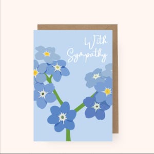 May include: A sympathy card featuring a blue background and a cluster of blue forget-me-not flowers. The text "With Sympathy" is written in white on the card.