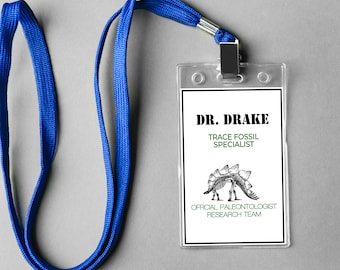May include: A blue lanyard with a clear plastic ID badge that reads "DR. DRAKE TRACE FOSSIL SPECIALIST OFFICIAL PALEONTOLOGIST RESEARCH TEAM" with a black and white illustration of a dinosaur skeleton.