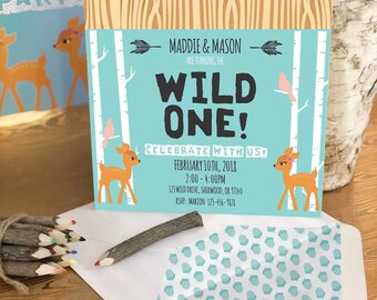 Può includere: Un invito alla festa Wild One con sfondo turchese, illustrazioni di cervi e il testo "MADDIE & MASON ARE TURNING THE WILD ONE! CELEBRATE WITH US!" L'invito include i dettagli dell'evento e articoli per la festa.