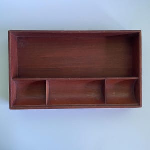 May include: A wooden tray with three compartments. The tray is a dark reddish brown color and has a smooth finish.