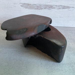 May include: A dark brown wooden box with a hinged lid. The box is made of a single piece of wood and has a natural, rustic look.