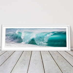 May include: A panoramic photograph of a large, turquoise wave crashing in the ocean. The wave is breaking and creating a spray of white foam. The water is a vibrant blue and green.