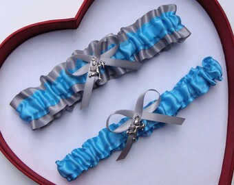 May include: Two blue and silver garters with a silver charm. The garters are made of satin ribbon and have a delicate, feminine design.