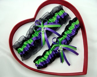 May include: A pair of garters with black, green, and purple satin ribbon and black lace. The garters have a silver charm with two hearts.