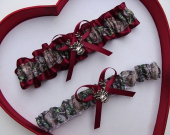 May include: Two burgundy and white garters with a camouflage pattern and a silver deer charm.