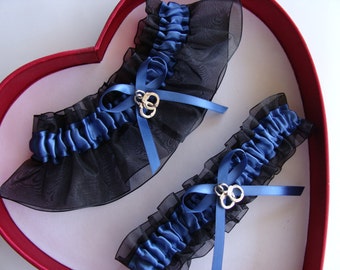 May include: Two blue and black garters with silver charm accents in a red heart-shaped box.