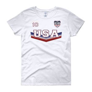 May include: White women's t-shirt with a red, white, and blue USA graphic and the number 10 on the front.