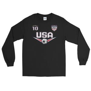 May include: Black long-sleeve t-shirt with a soccer theme. It features a white and red USA logo, a soccer ball, and the number 10.