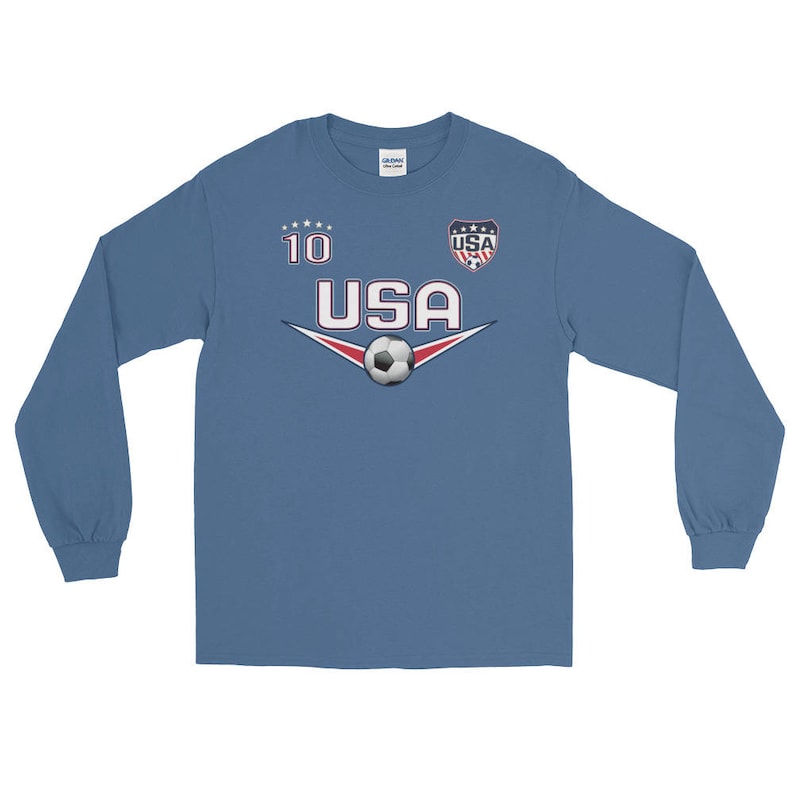 May include: A blue long-sleeve shirt with a white soccer jersey design. The shirt has the number "10" and the word "USA" with a soccer ball and a small USA flag.