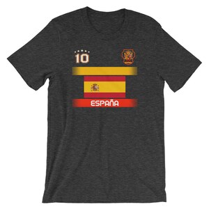 May include: Dark gray t-shirt featuring the Spanish flag design. The shirt has the number 10 and the word "Espa&ntilde;a" in red. The design includes a gold and red horizontal stripe and a crest.