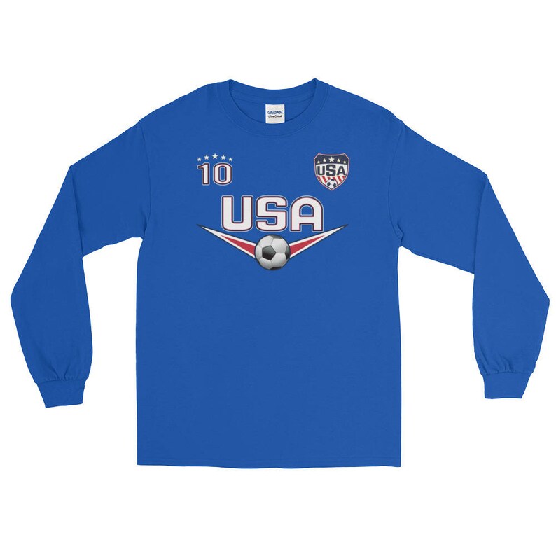 May include: A royal blue long-sleeve shirt with a white soccer ball and the text "USA" in a white, red, and blue font. The number "10" is printed in white above the text. A small USA flag is printed in the top right corner.