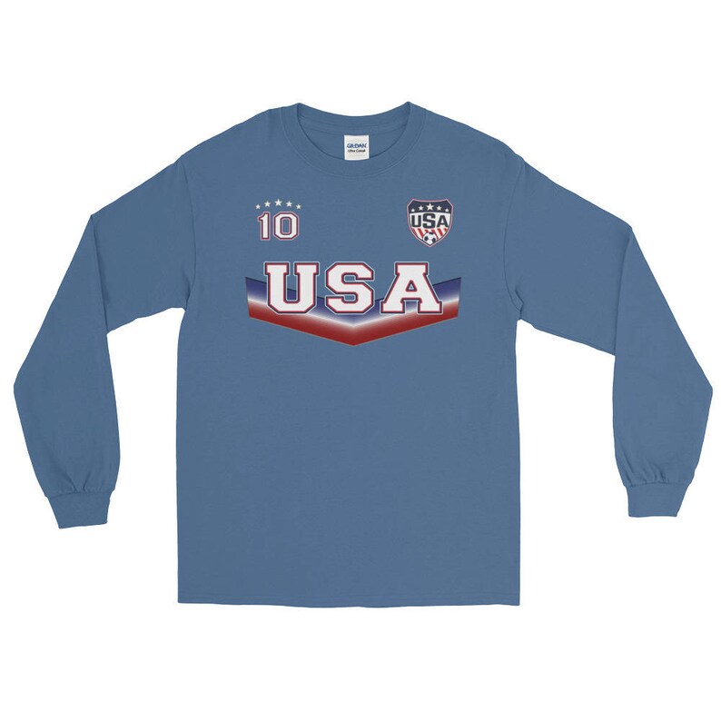 May include: A long-sleeved, blue t-shirt with a red, white, and blue USA graphic. The graphic includes a soccer ball and the number 10.