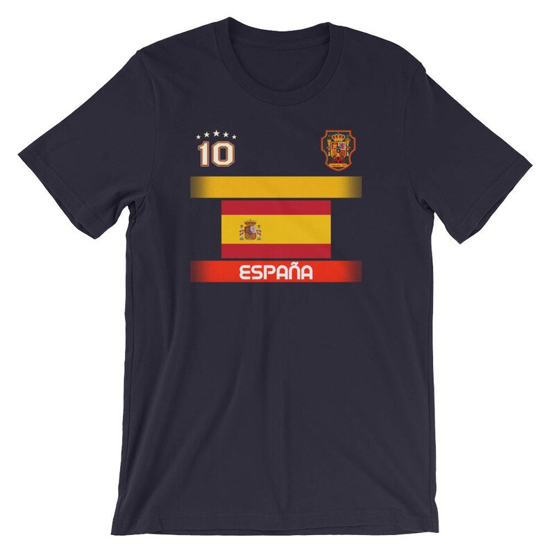 May include: Navy blue t-shirt featuring the Spanish flag design. The shirt includes the number 10, a crest, and the word "Espa&ntilde;a" in white. The design incorporates the colors red, yellow, and white.