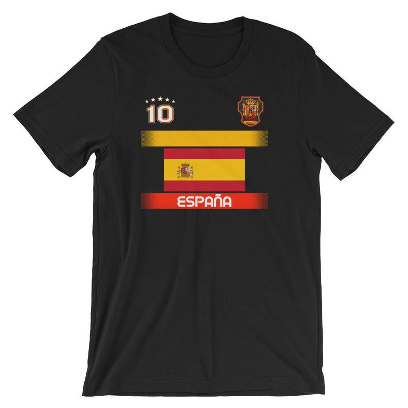 May include: Black t-shirt featuring the Spanish flag design. The shirt has the number 10 and the word "Espa&ntilde;a" in white. The design includes a gold and red color scheme, with a crest on the upper right.