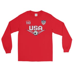 May include: Red long-sleeve shirt with a white and blue USA soccer jersey design. The shirt has a white soccer ball graphic and the number 10 on the front.